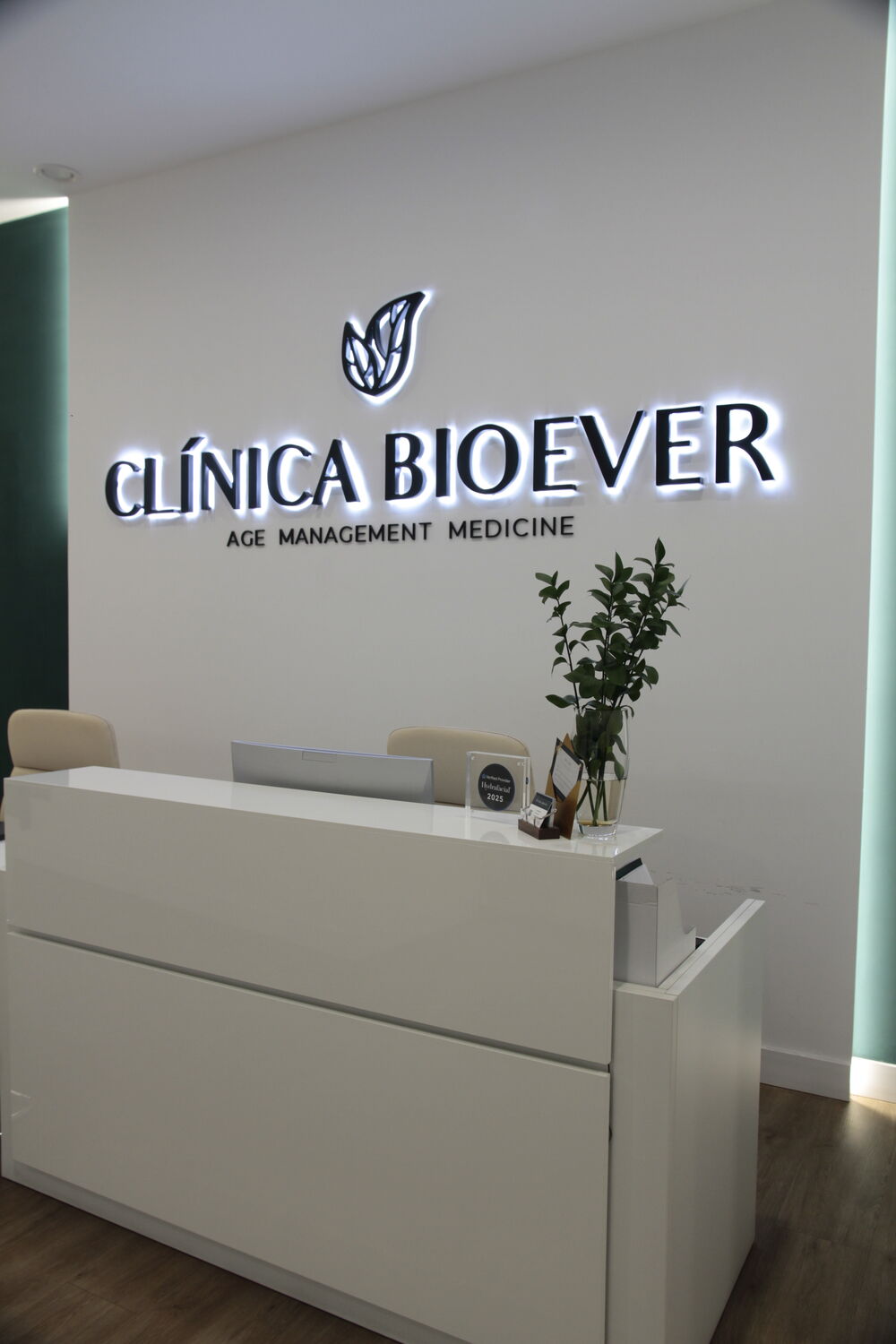 Recepción de Clínica Bioever con el logotipo de la clínica iluminado en la pared
